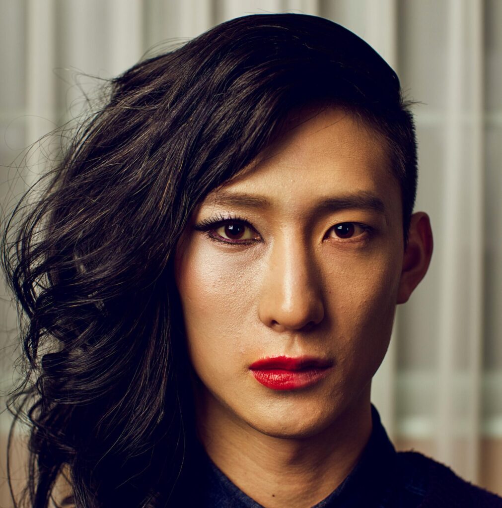 Androgynous model showcasing bold makeup and unique hairstyle.